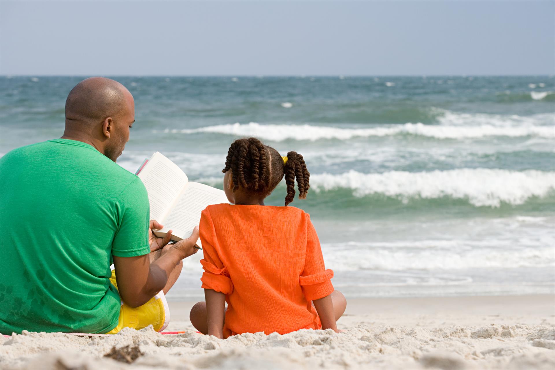 Father and daughter studying on the beach