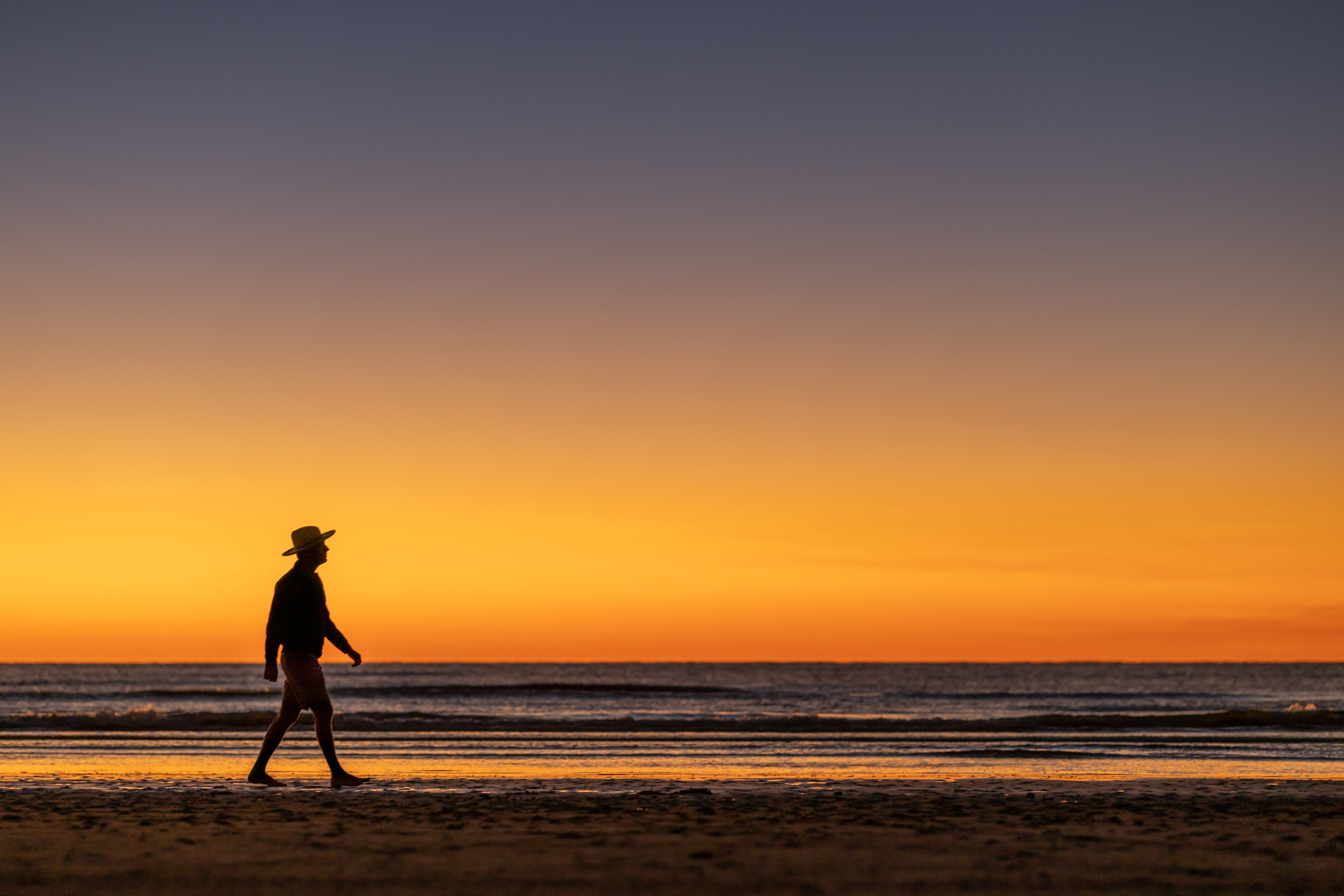 man walking on beach at cinnamon shore