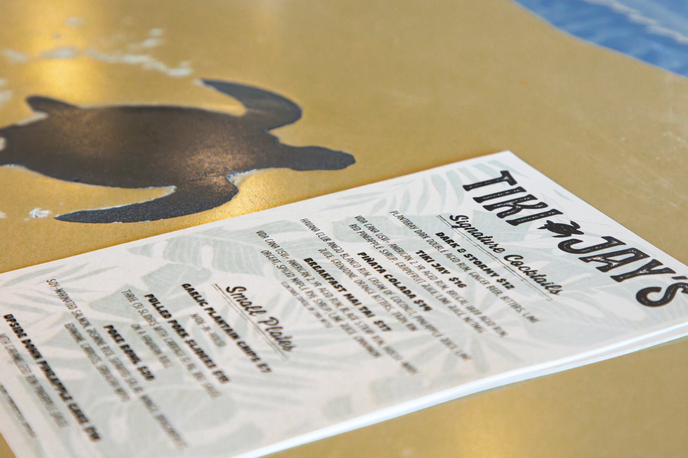 Tiki Jay's menu on a table at Cinnamon Shore, featuring seafood, poke bowls, and cocktails in Port Aransas