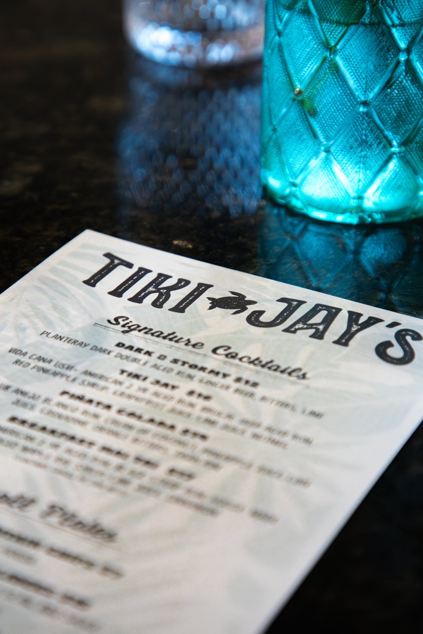 Tiki Jay's menu beside a tropical cocktail glass at Cinnamon Shore in Port Aransas