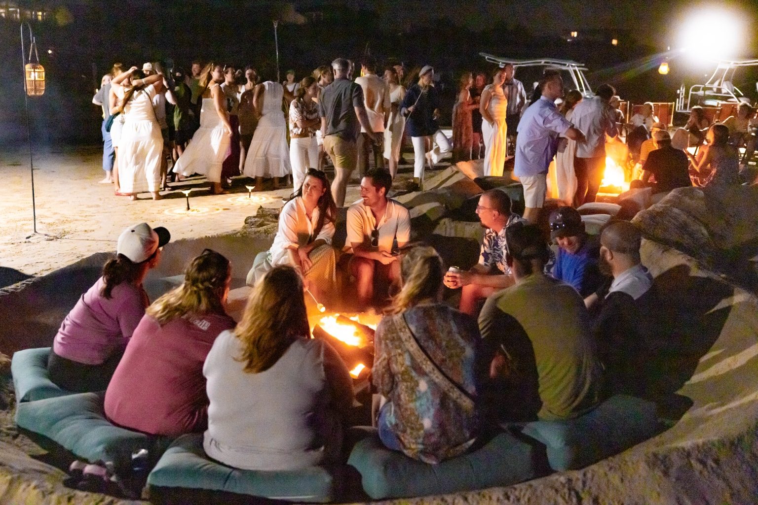 Guests relax by a private Cinnamon Shore beach bonfire with Gulf views, soft seating, and evening event lighting.