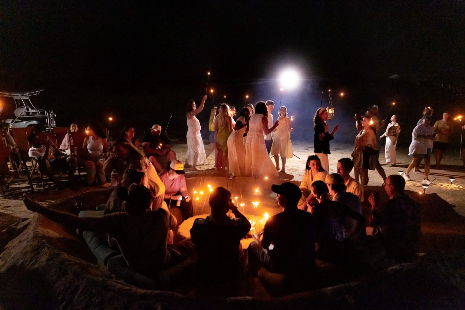 Guests gather around a premium beach bonfire with sparklers, live music, and Gulf-side seating at Cinnamon Shore.