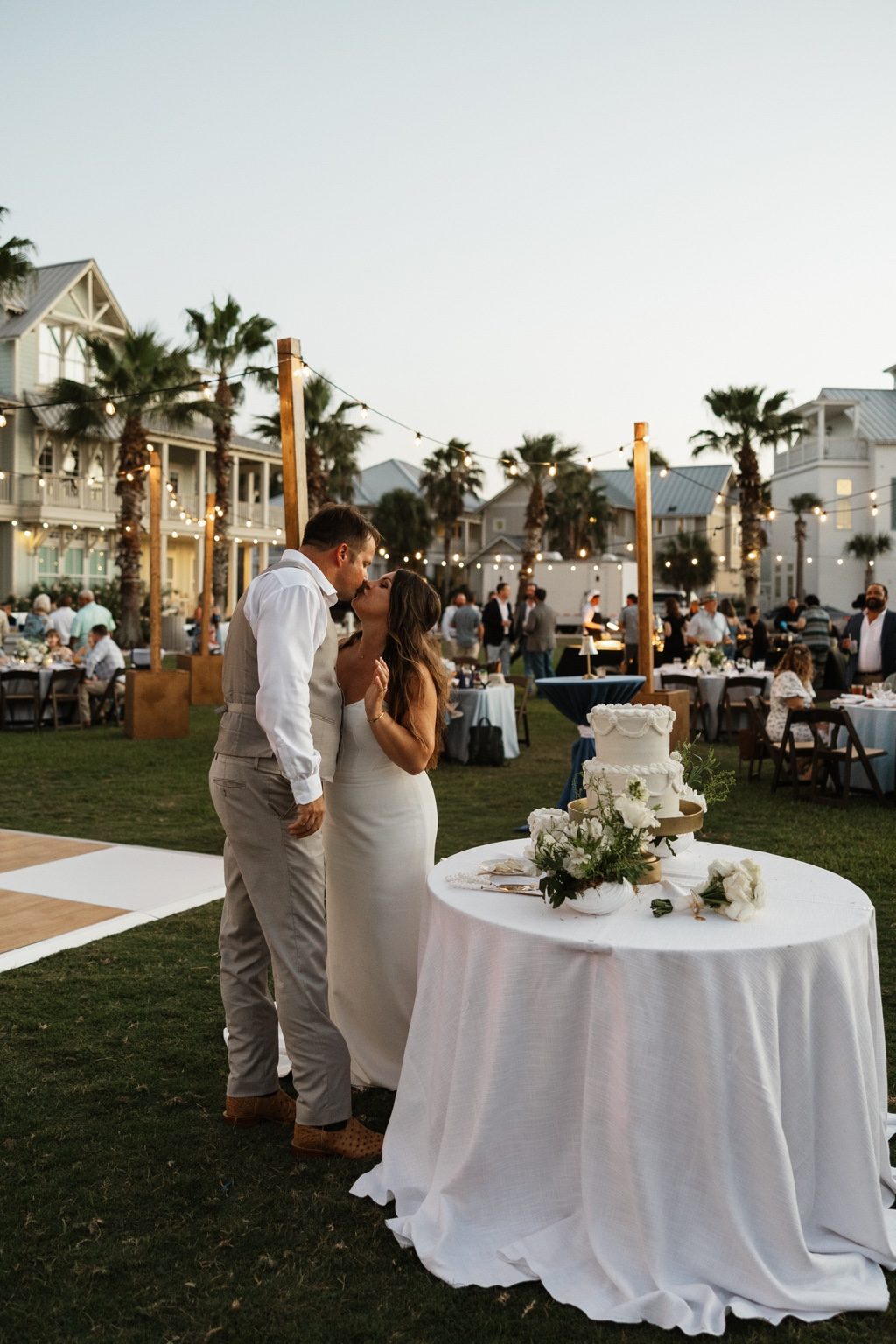 Wedding couple celebrating at an outdoor Cinnamon Shore reception with guests, coastal homes, and string lights in Port Aransas, Texas