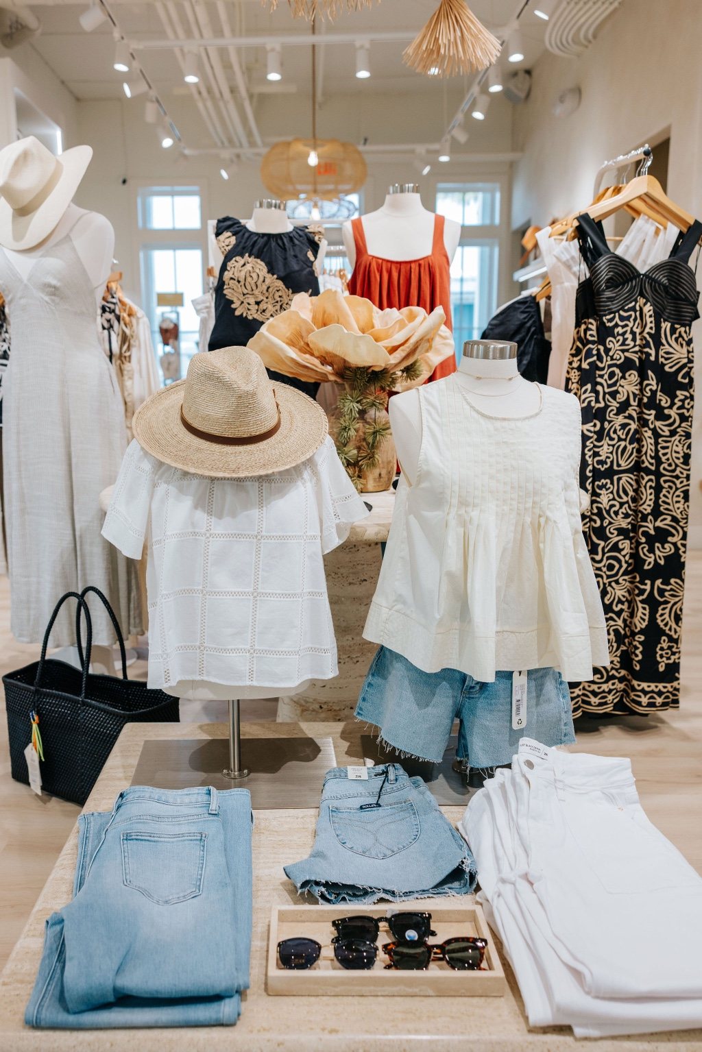 The Boutiques at Cinnamon Shore resort wear display with summer outfits, denim, hats, and sunglasses on Market Street