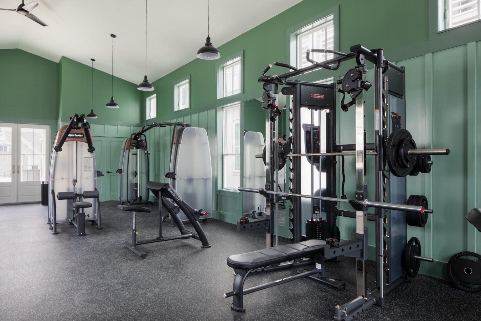 Glow Pool Fitness Center strength training and weight equipment in a green fitness room at Cinnamon Shore.