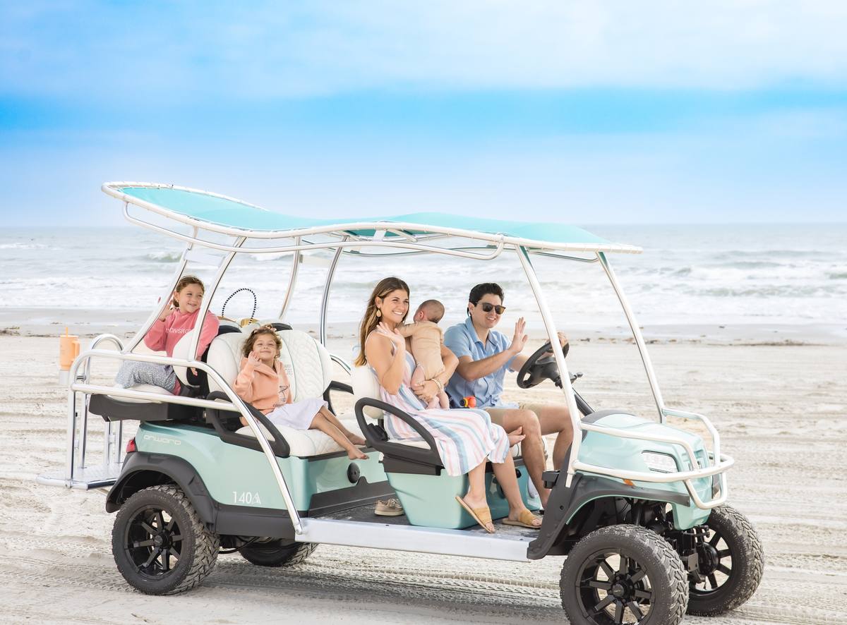 Family riding a six-seater golf cart on the beach at Cinnamon Shore in Port Aransas, Texas