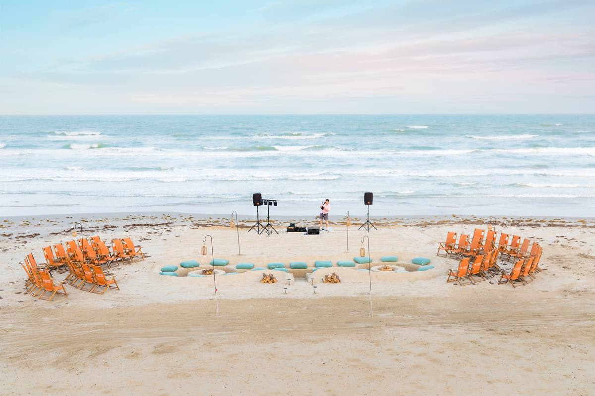 Aerial view of the full Twin Ember twin-seating bonfire layout on the beach with the Gulf in the background at Cinnamon Shore.