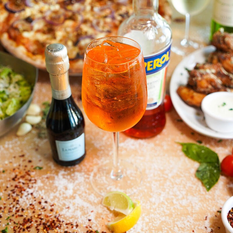 Aperol spritz served with pizza, salad, and appetizers at Dylan's