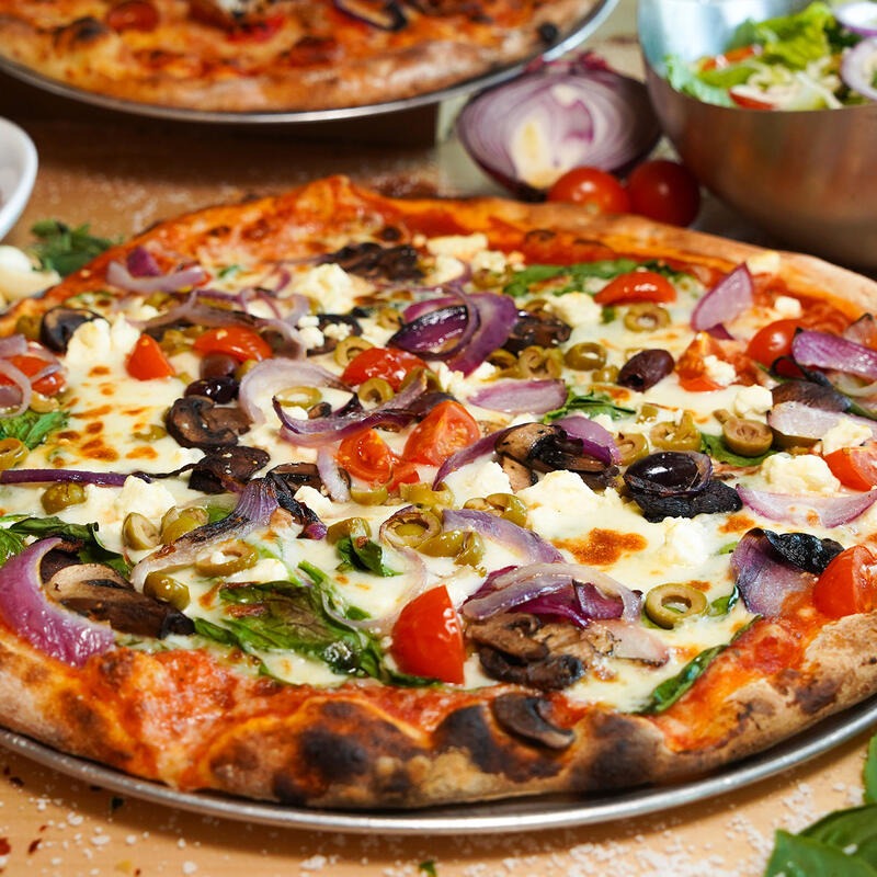 Dylan's veggie pizza topped with mushrooms, red onion, olives, tomatoes, and greens