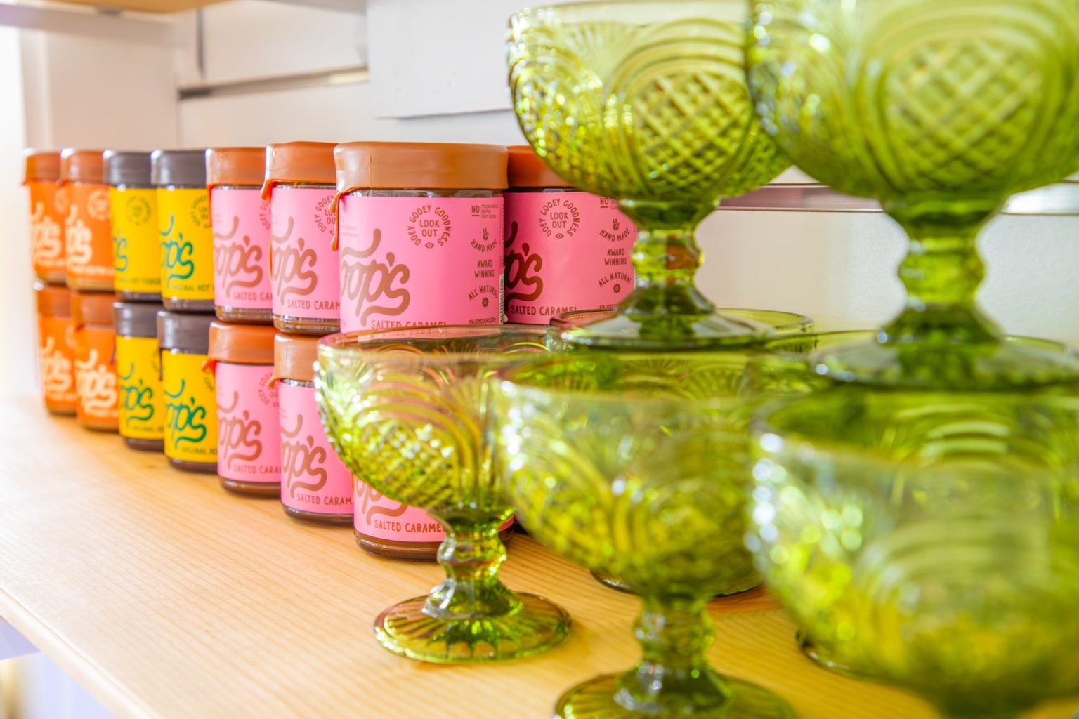 Gourmet sauces and green glassware on the shelves at Saltwater Gypsies Market