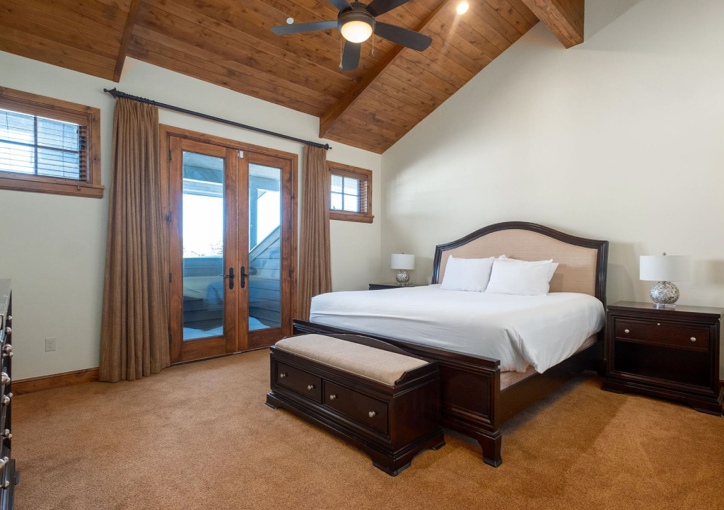 Large, rustic bedroom with French doors leading to a deck.