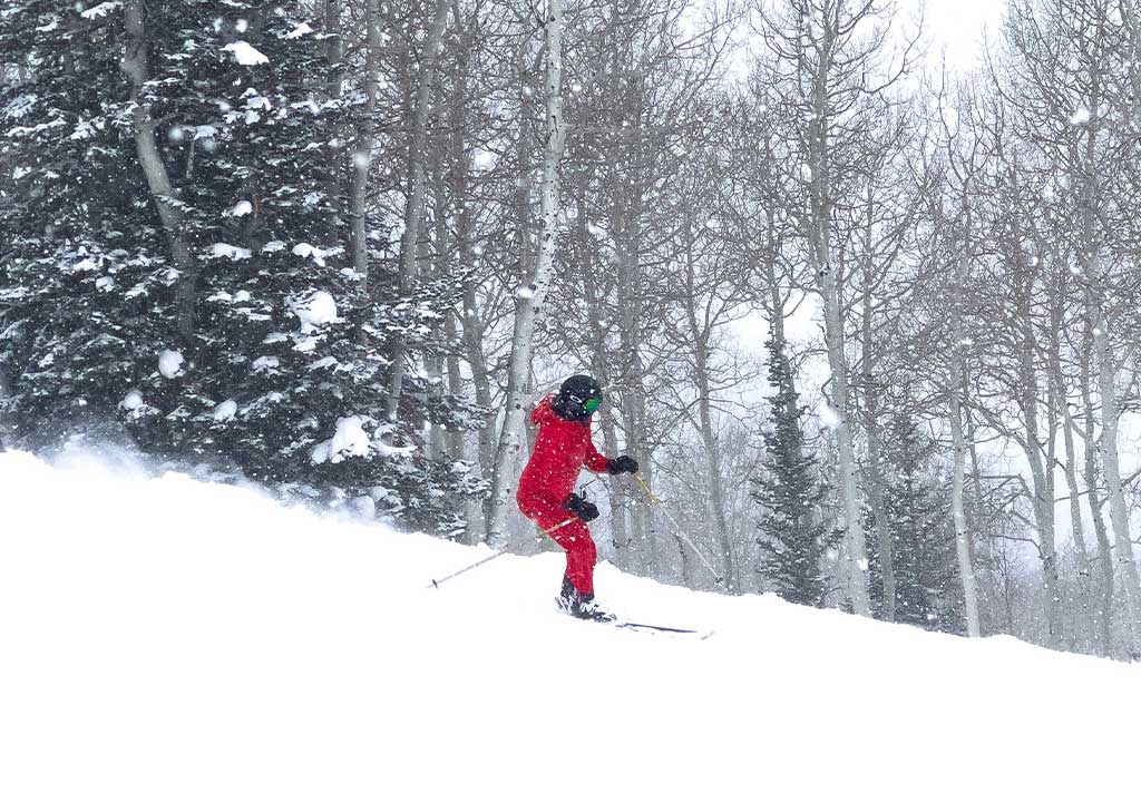 A person skiing in snow down slope.