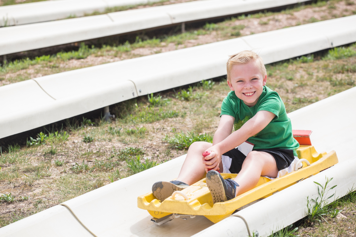 A smiling kid on the an alpine slide.