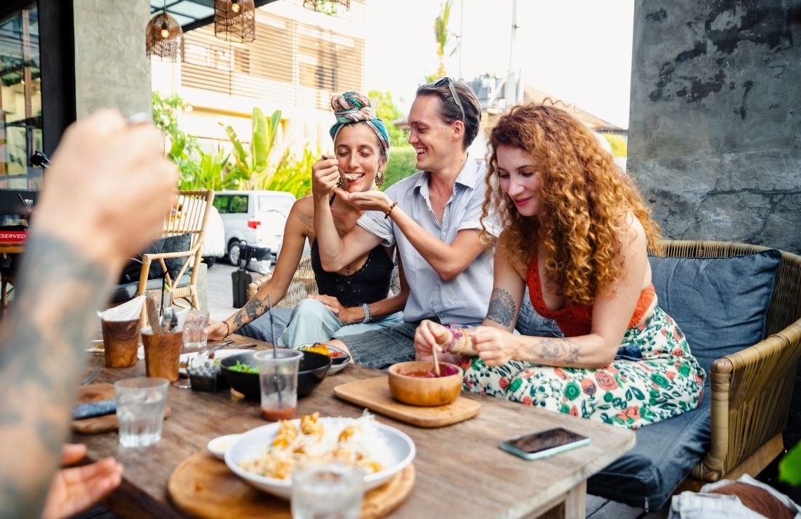 A group of three friends sitting outside on the patio, eating delicious food in Park City.