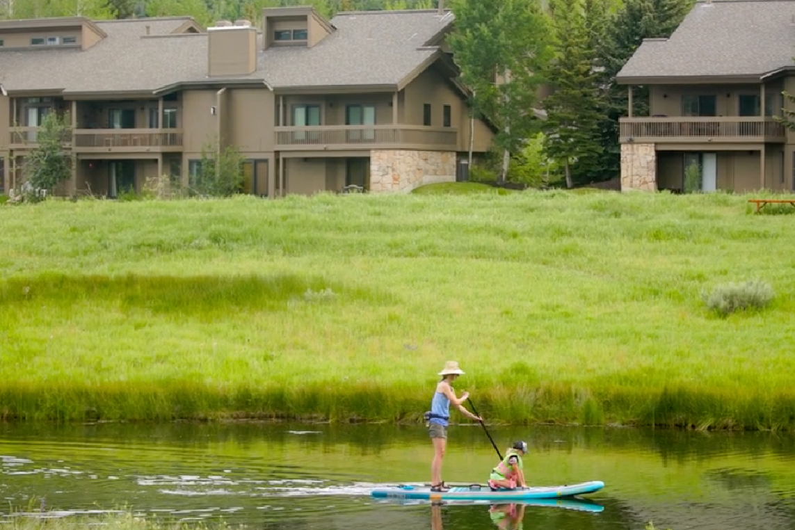 Two people standup paddleboard (SUP) in Park City, Utah during their summer vacation.