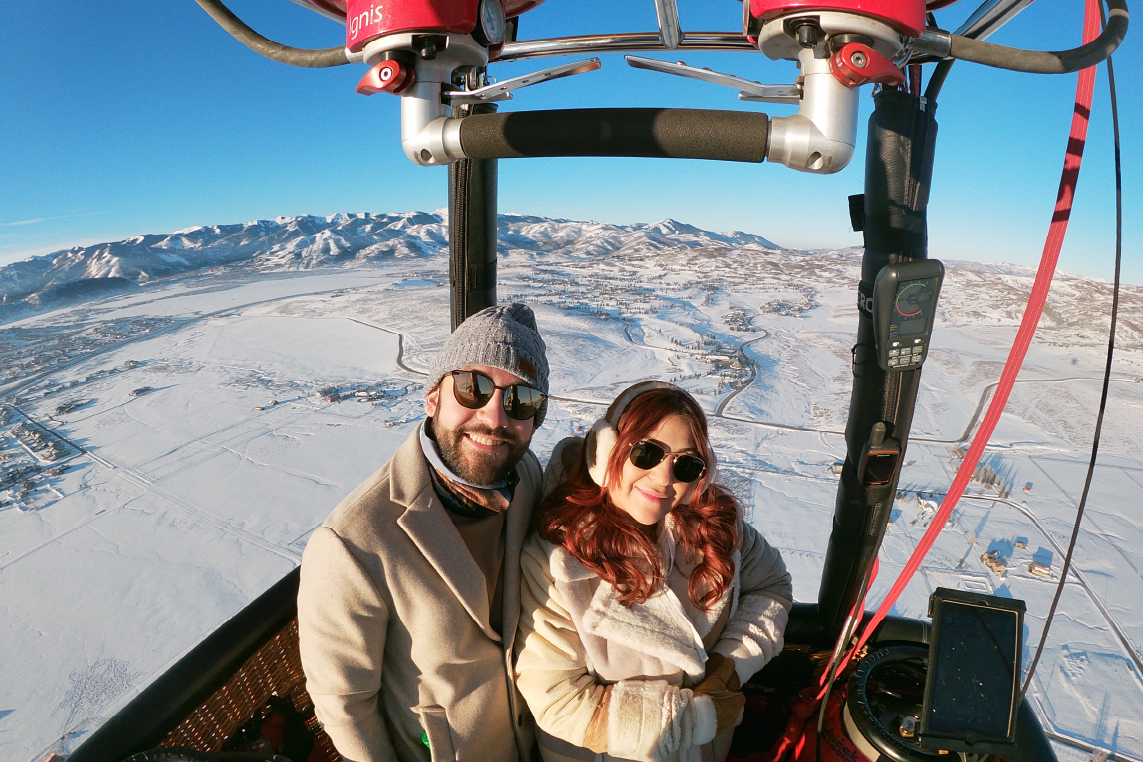 A man and woman take a romantic hot air balloon ride over Park City during the winter.