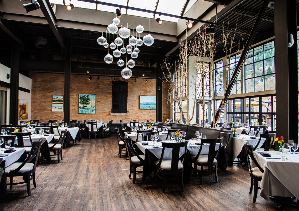 Inside of Riverhorse on Main featuring dark wood floors, finely dressed tables, and big open windows.