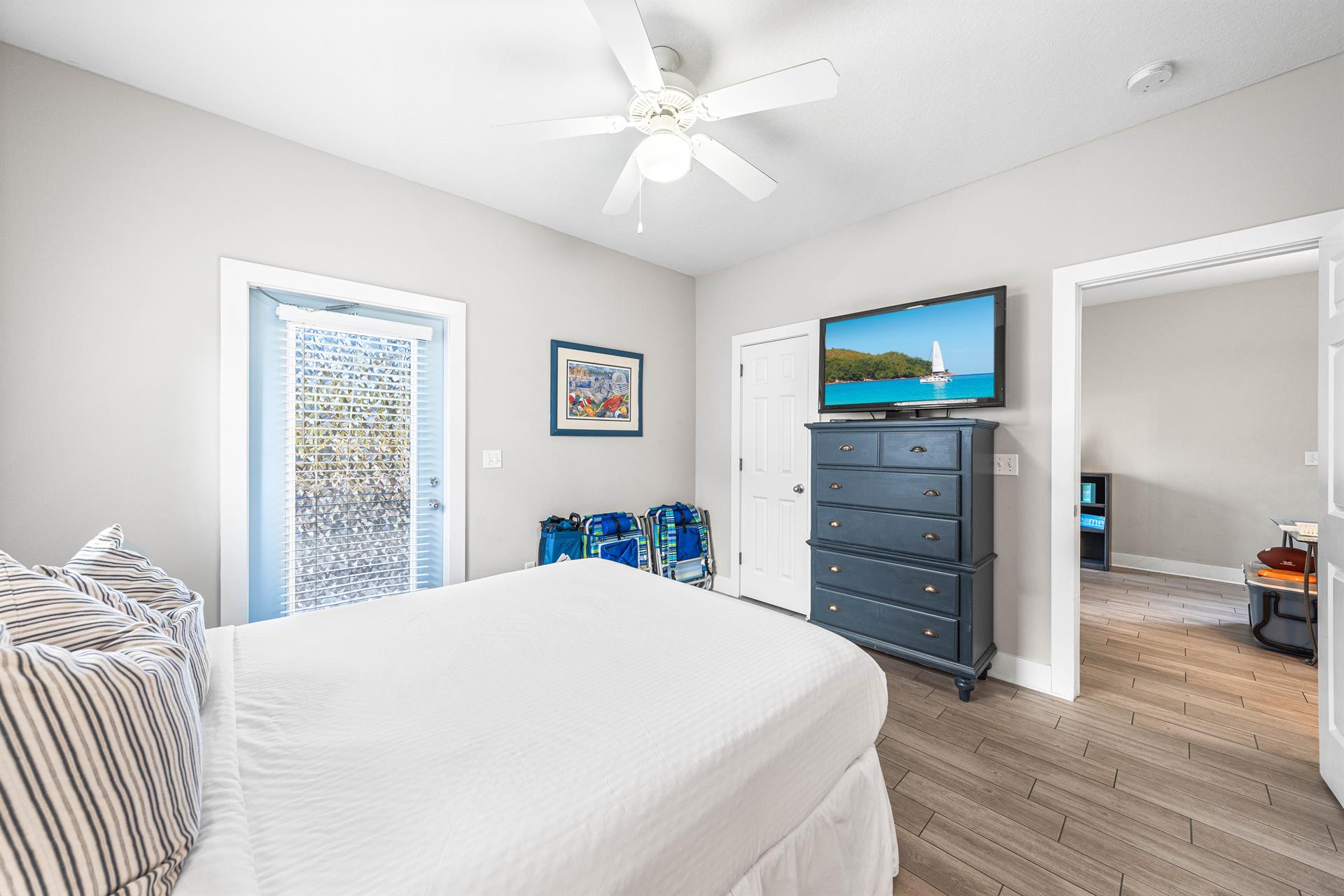 Another view of the first floor bedroom with a queen bed,42 tv, large walkin closet, additional door out to the front porch, and a full bathroom.