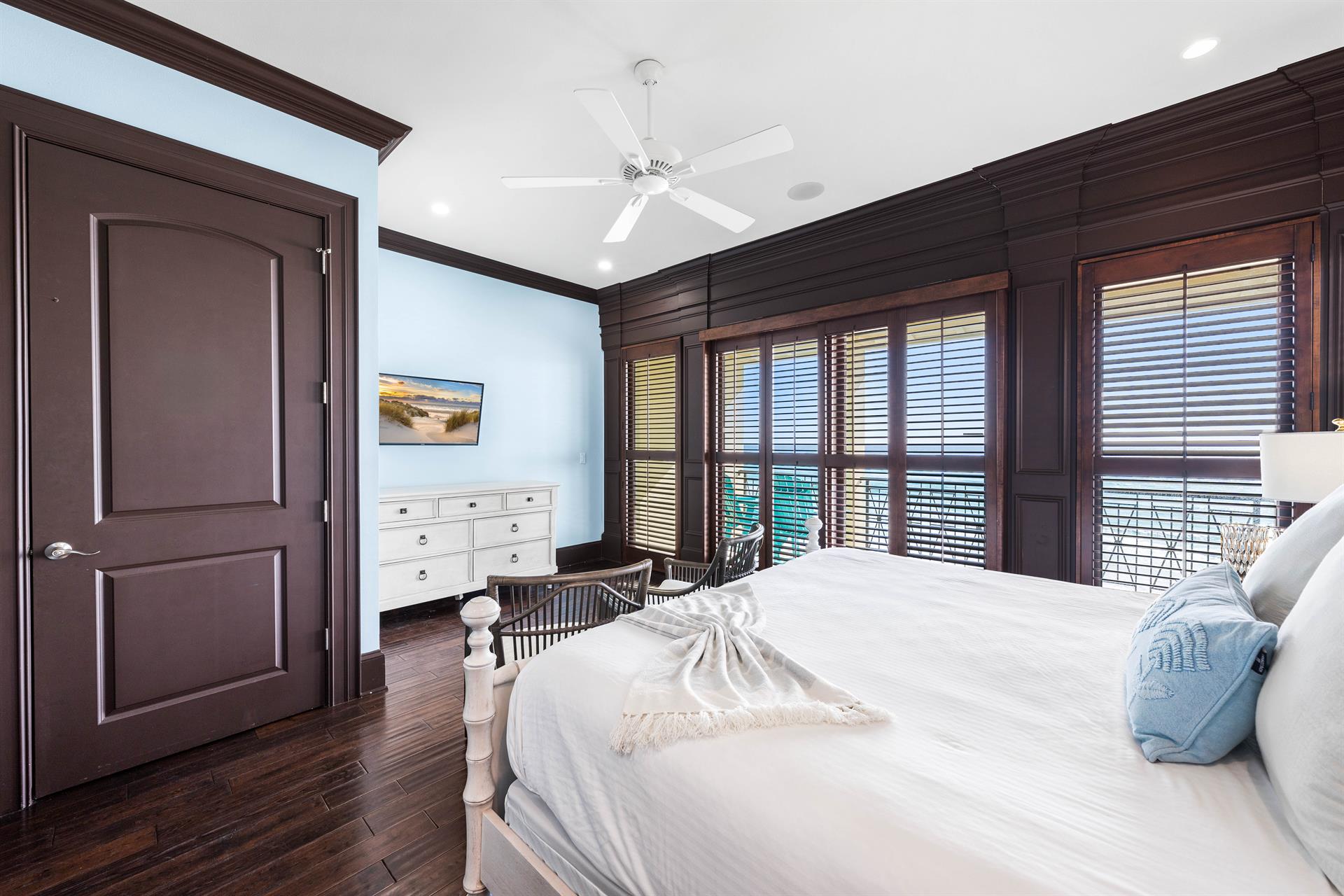 Third floor primary bedroom with king bed, ensuite bathroom, wet bar with beverage cooler  Keurig coffee setup, walkin closet, 42 smart tv, sliding plantation shutters, elevator access  beachfront balcony with seating.