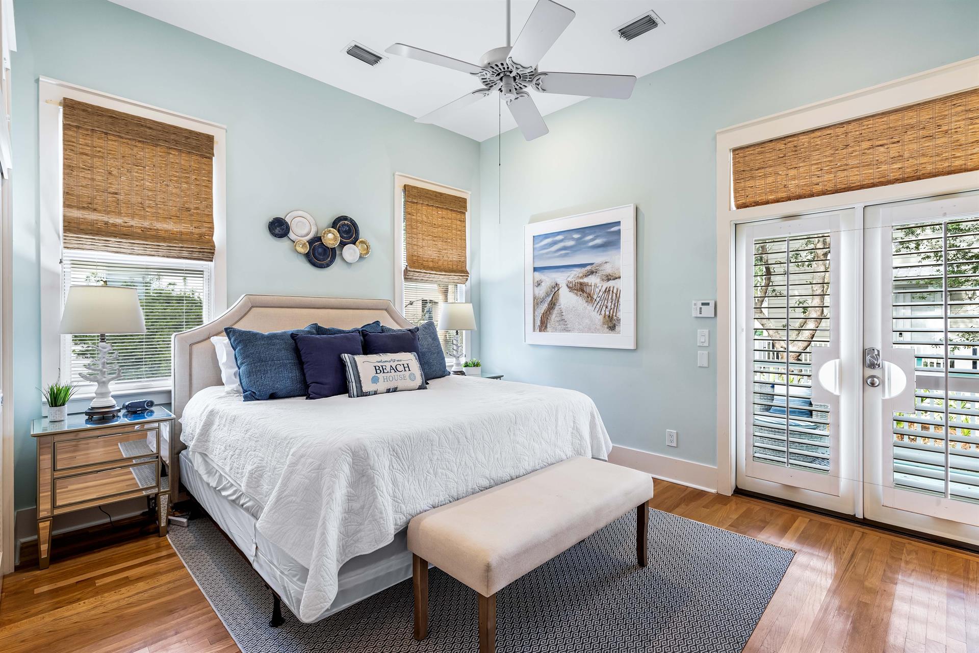 Hardwood floors, woven shades plus plantation shutters give this primary bedroom a sense of sophistication and serenity.