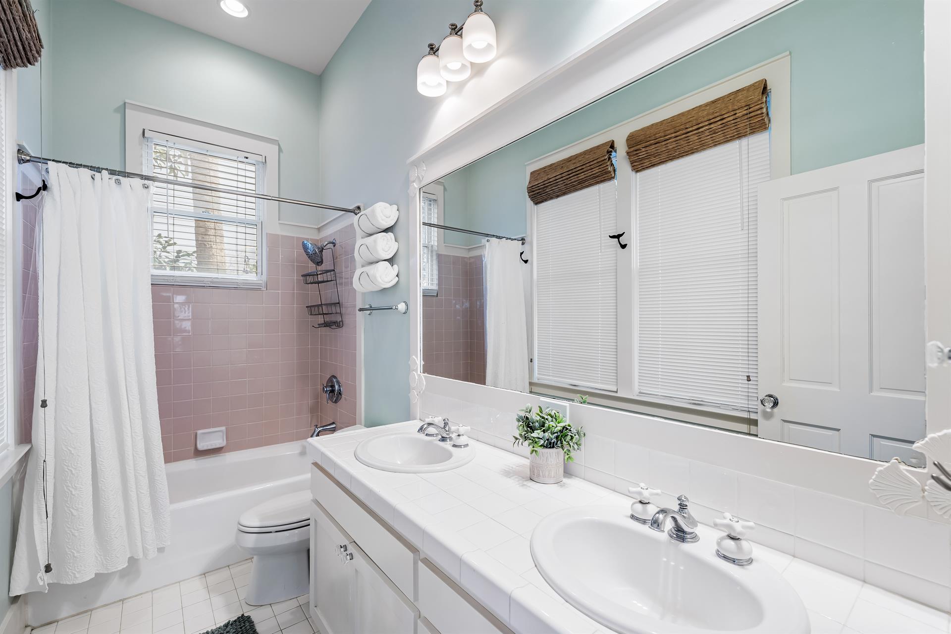 The primary bathroom features 2 sinks and a bathtub with shower providing an aesthetic appeal.