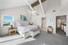 Lofted ceiling with white beams give this primary king bedroom a light and airy feel.