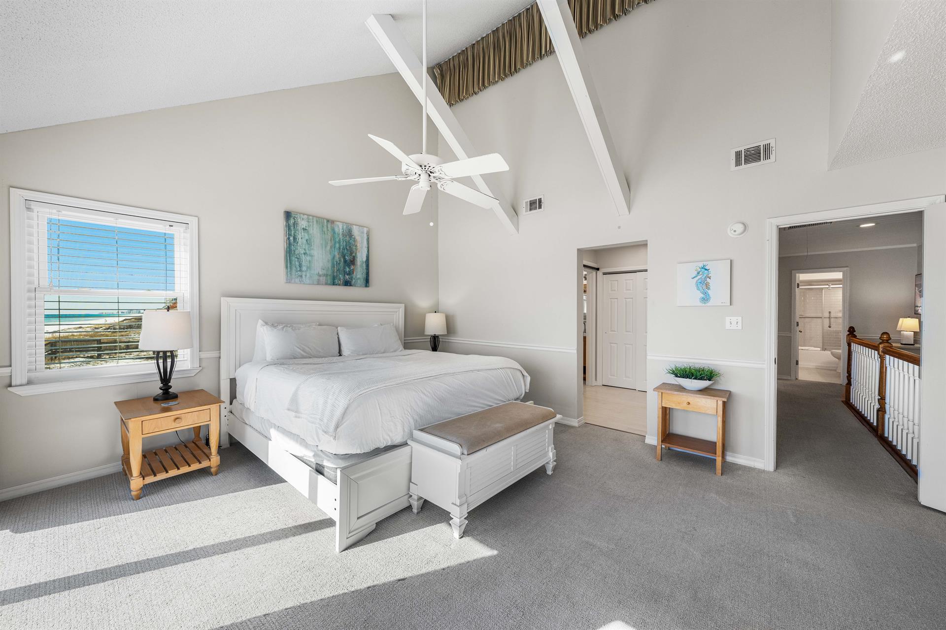 Lofted ceiling with white beams give this primary king bedroom a light and airy feel.