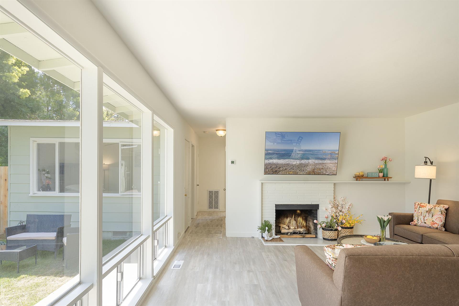 Living Room has a Gas Fireplace, TV and a Wall of Windows