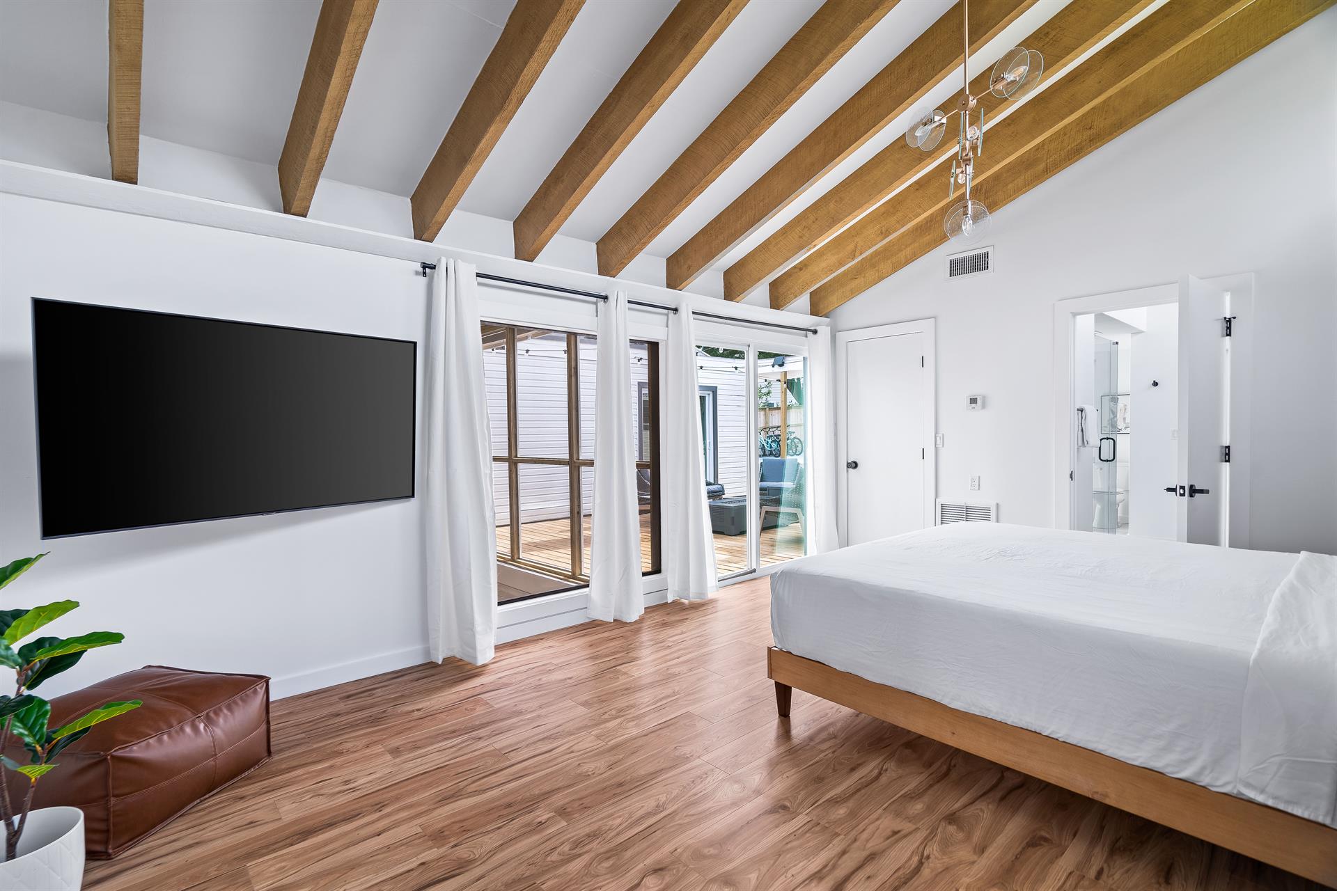 King bed primary bedroom with large flat screen tv and sliding door opening to the pool deck area. Bedroom 1