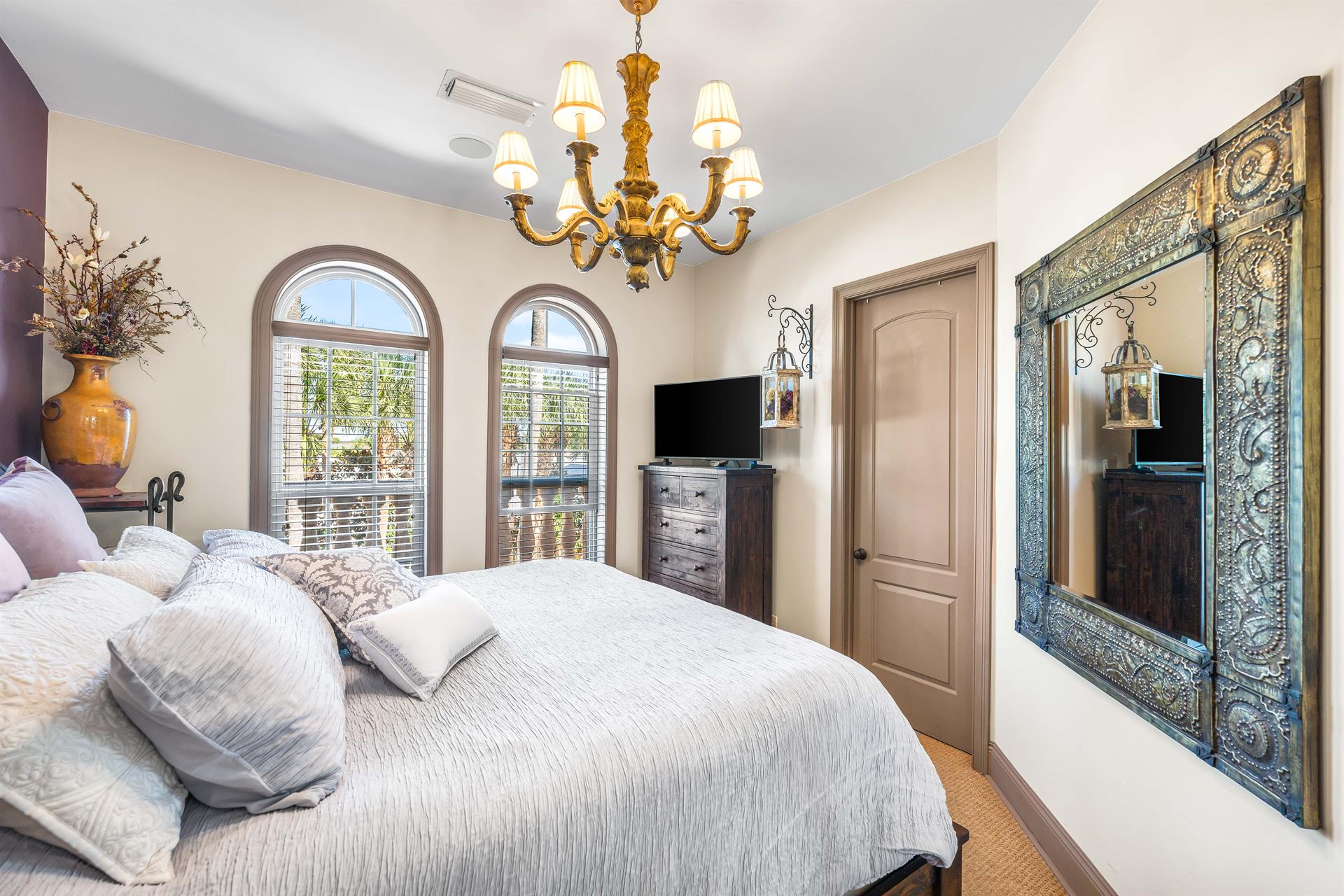 Arched windows provide natural light into this primary king bedroom with spacious walkin closet and a 42 smart tv.