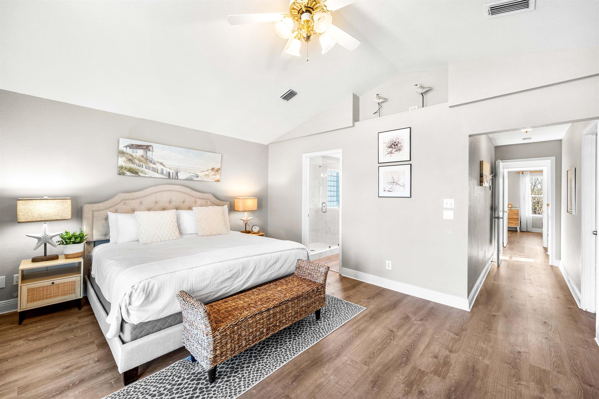 Primary King Bedroom with Private Balcony, Ensuite Bathroom, and 55 Smart TV.  Hallway separates the 2 upstairs bedrooms providing privacy.