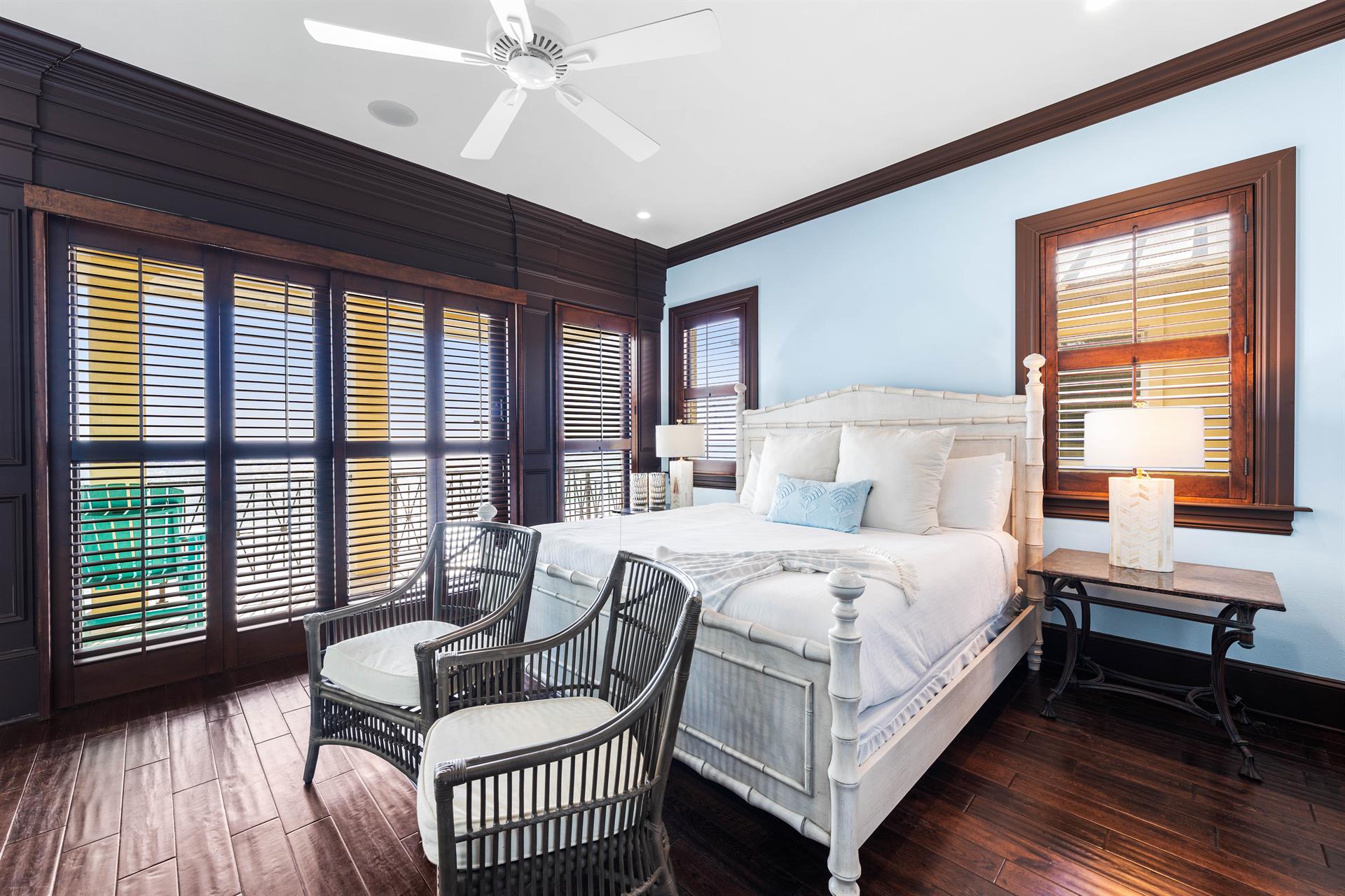 Third floor primary bedroom with a king bed, ensuite bathroom, wet bar with beverage cooler and Keurig coffee setup, walkin closet, 42 smart tv, sliding plantation shutters, and beachfront balcony with seating.