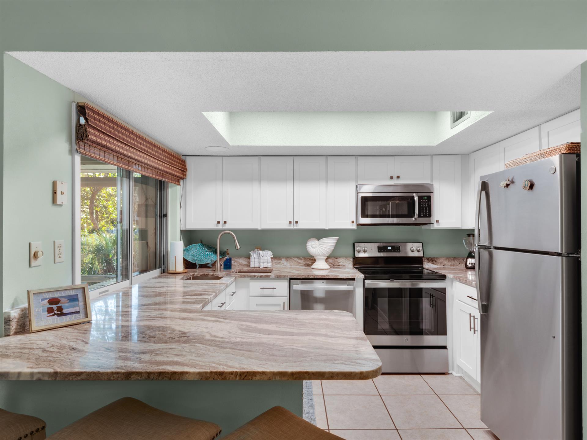 Spacious Kitchen with Bar Seating and Window to Screened Patio