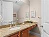 Half bathroom featuring granite countertops, warm wood cabinetry, and thoughtful coastal artwork that creates a serene atmosphere for your daily routine.
