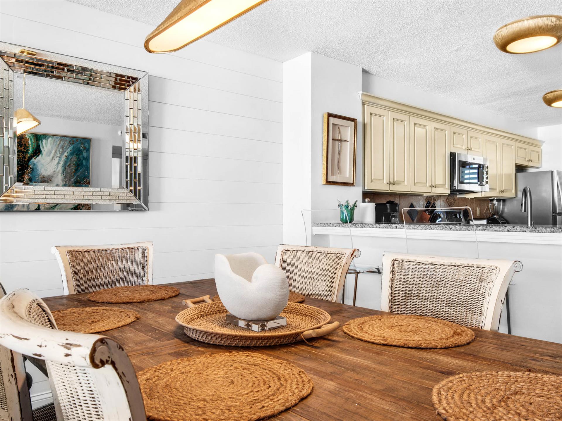 Gather around your beautifully appointed dining table for memorable meals, with elegant wicker placemats and a stunning oceaninspired mirror creating the perfect atmosphere.