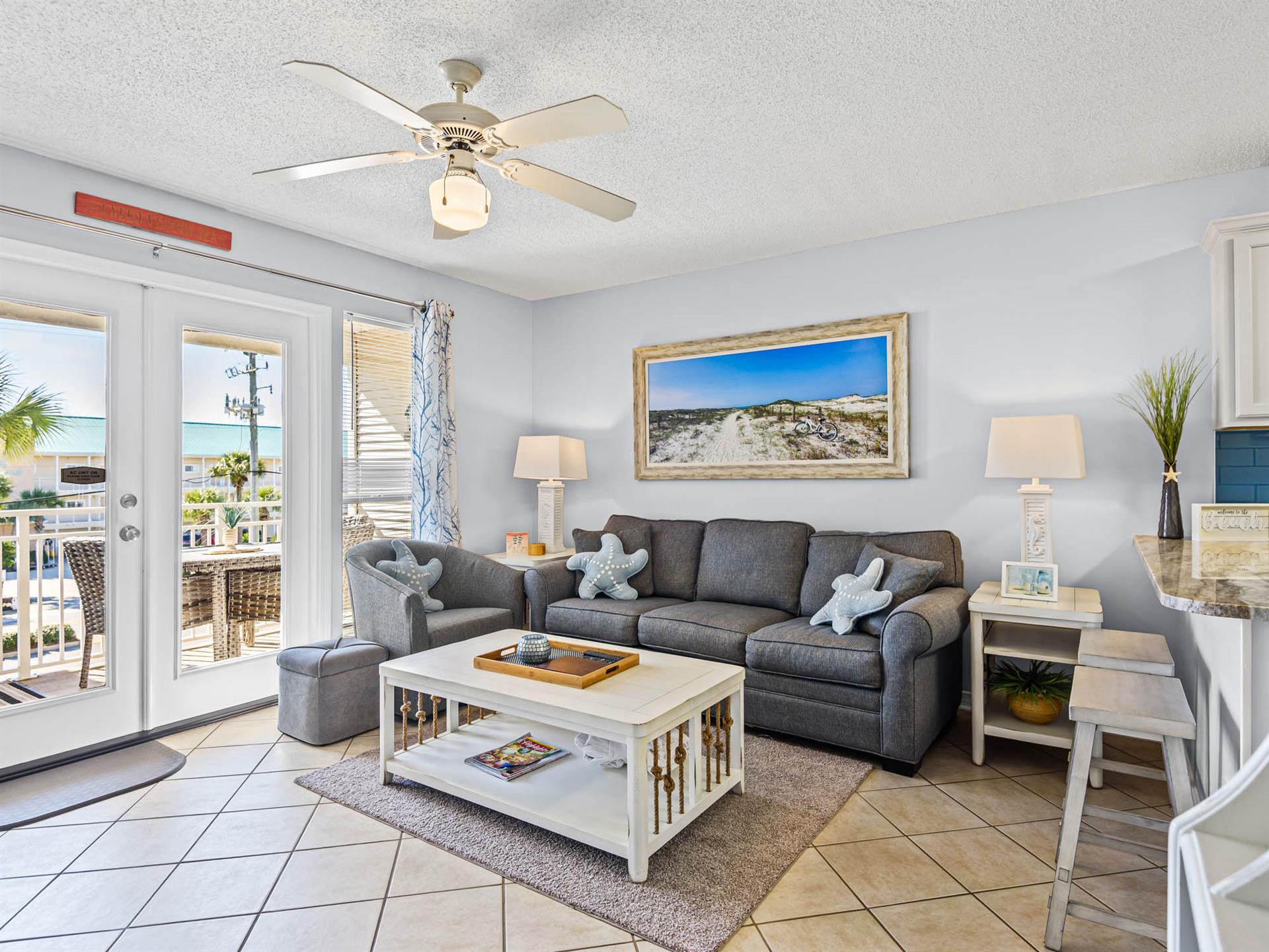 Relax in the coastal living room with plush seating, ceiling fan, and beachthemed decor creating the perfect vacation atmosphere.