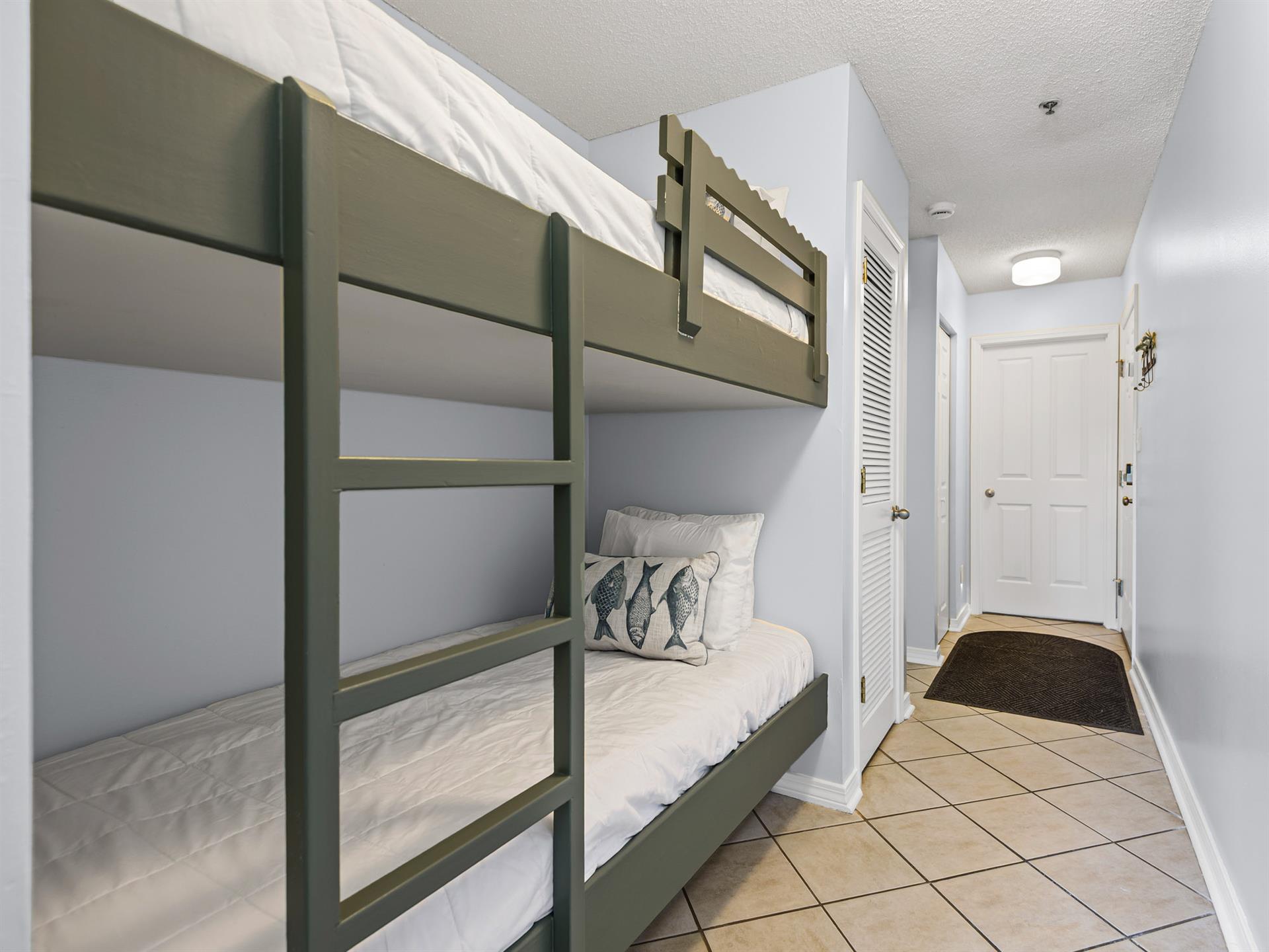 The familys bunk bed nook offers cozy sleeping for kids, complete with soft linens and nautical touches in this tiled hallway entry.