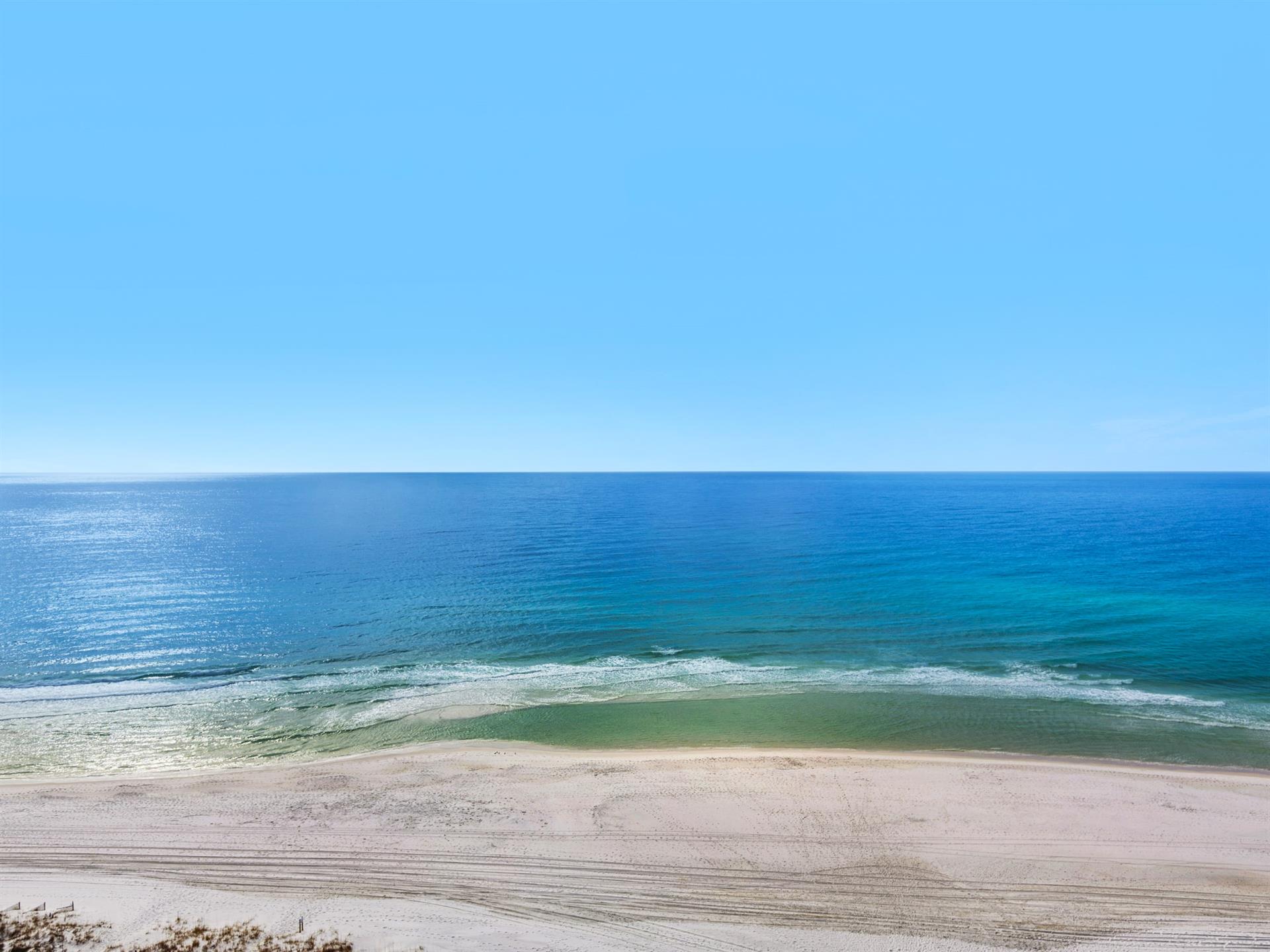 Pristine beach with crystalclear turquoise waters and soft sand stretches endlessly along the coastline under brilliant blue skies.