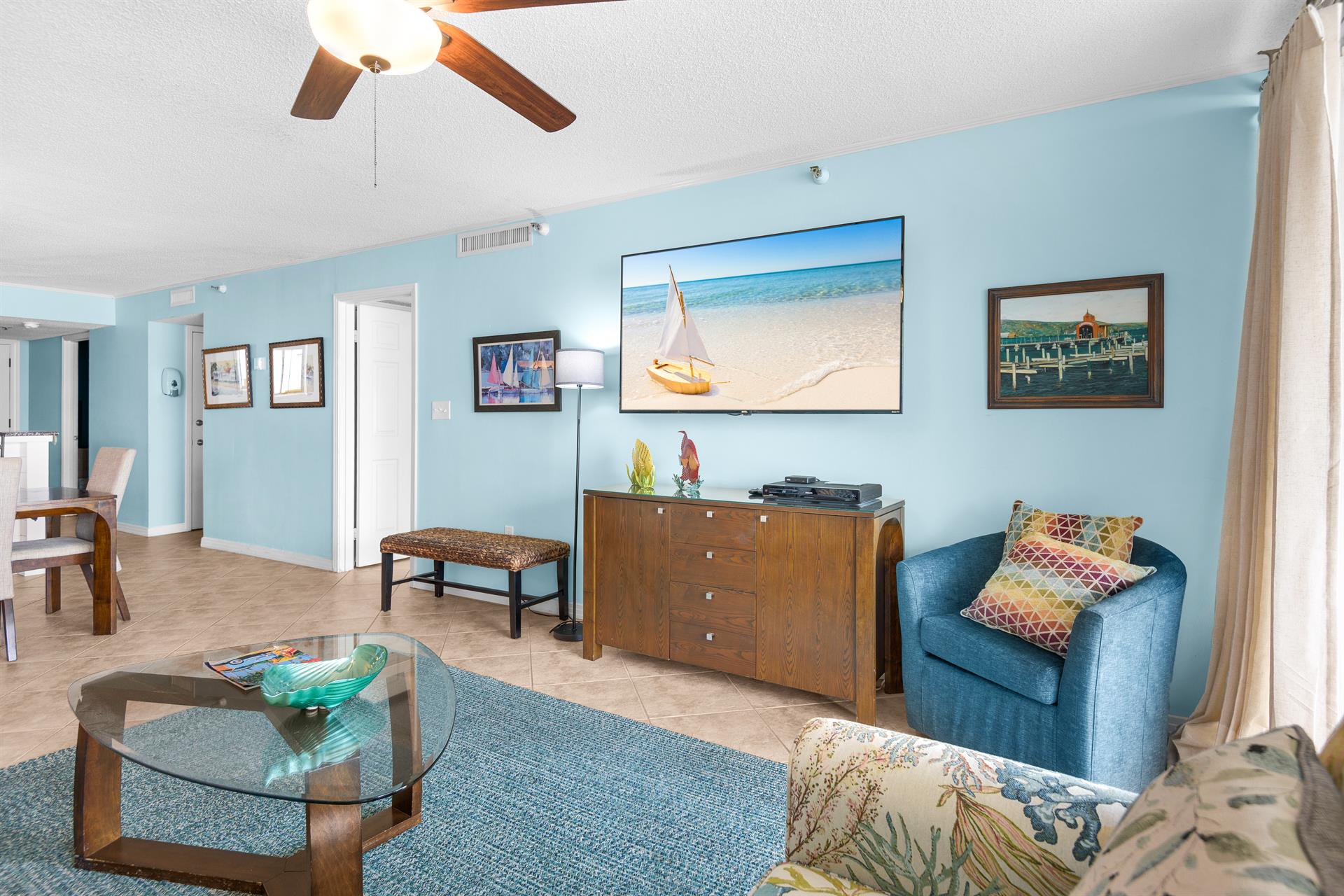 Relax in your coastalthemed living space with soothing blue tones, beach artwork, and comfortable seating perfect for unwinding after sunny days.