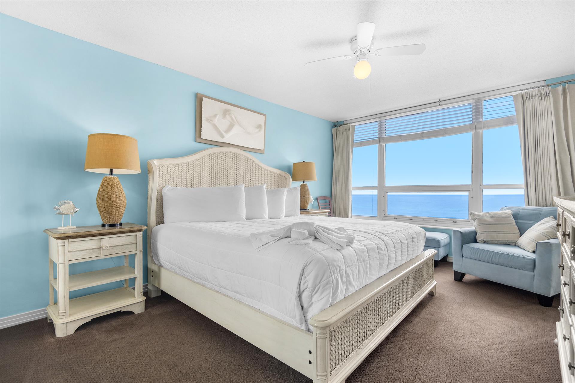 Wake up to breathtaking ocean views from your comfortable bed. Soft blue walls and coastal furnishings create a serene retreat.