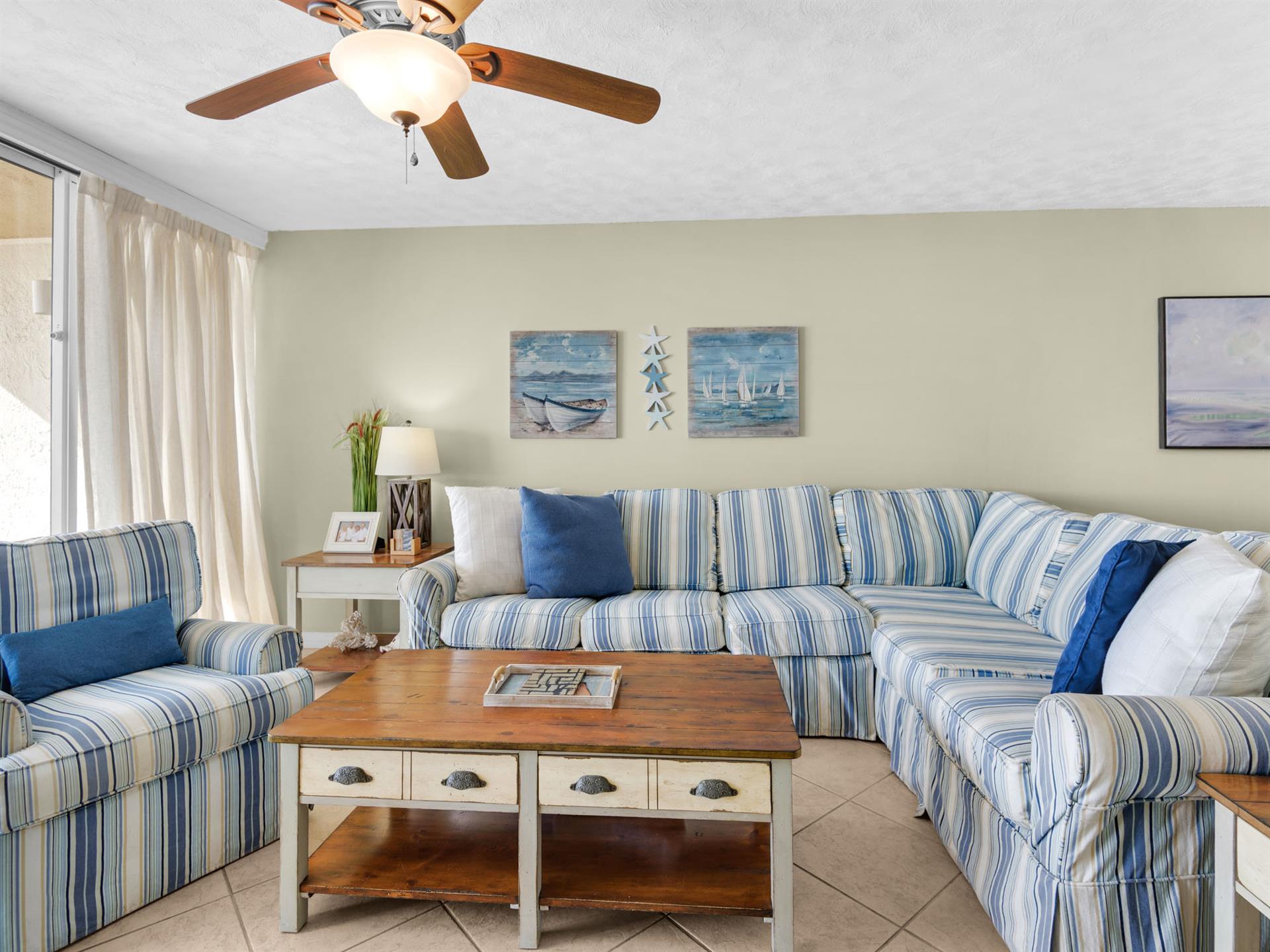 Sink into the plush striped sectional sofa where coastal artwork and soft blues create your perfect seaside retreat.