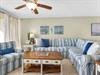 Sink into the plush striped sectional sofa where coastal artwork and soft blues create your perfect seaside retreat.