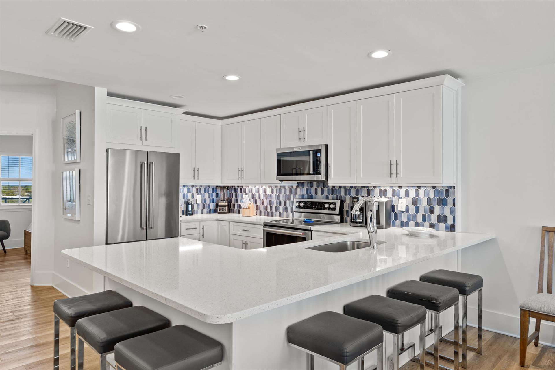 Your fully equipped kitchen features gleaming quartz countertops, stainless steel appliances, and a breakfast bar perfect for morning coffee.
