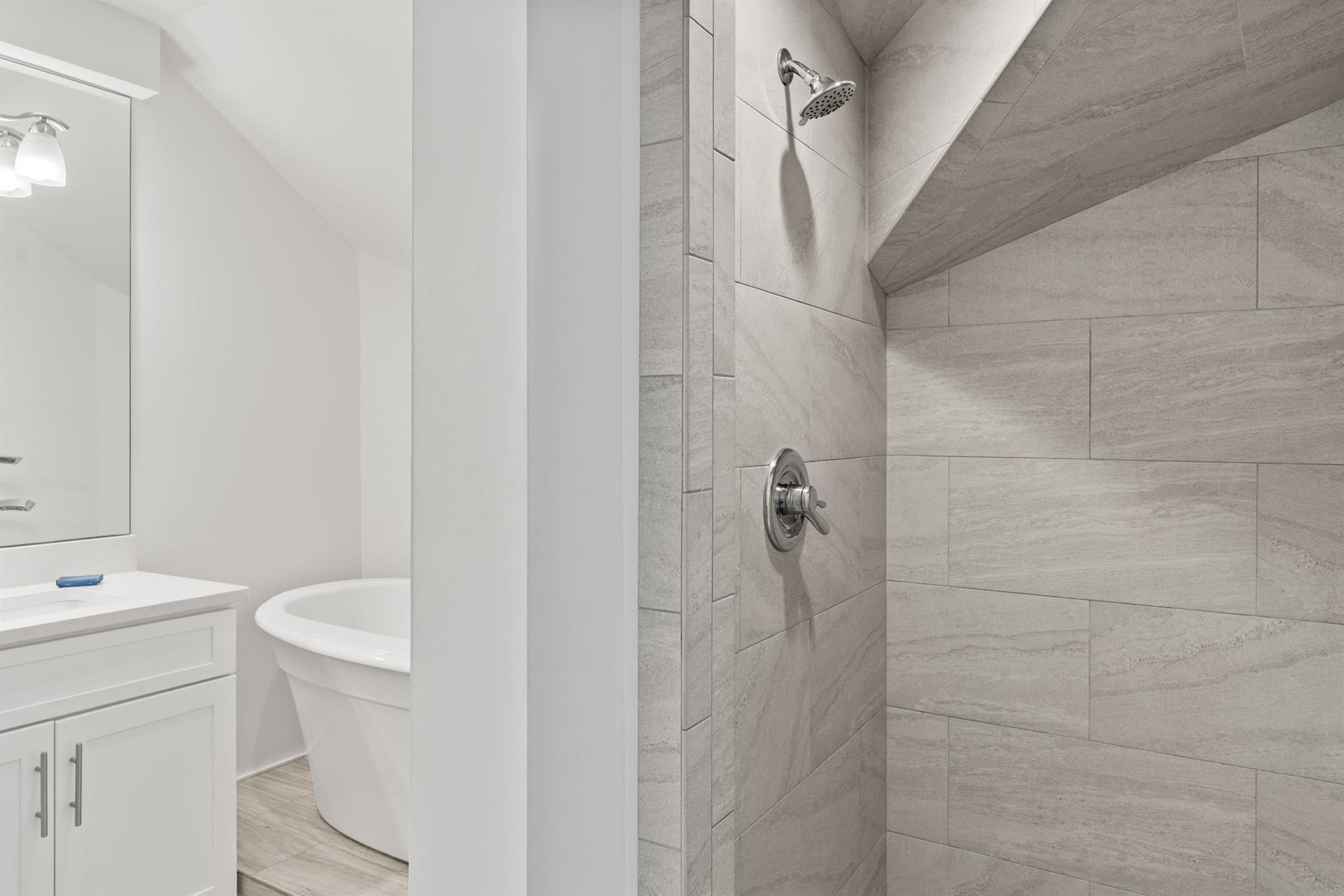 Indulge in your private spalike retreat with a luxurious soaking tub and rainfall shower, all wrapped in elegant stone tile.
