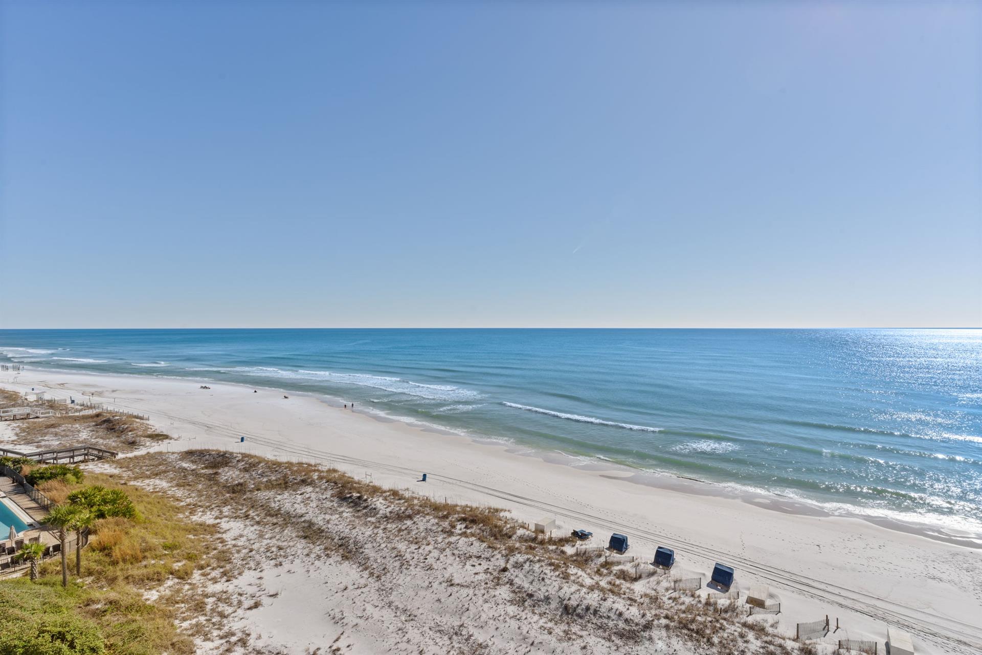 Pristine white sand beach stretches endlessly along crystalclear emerald waters with gentle waves rolling to shore.