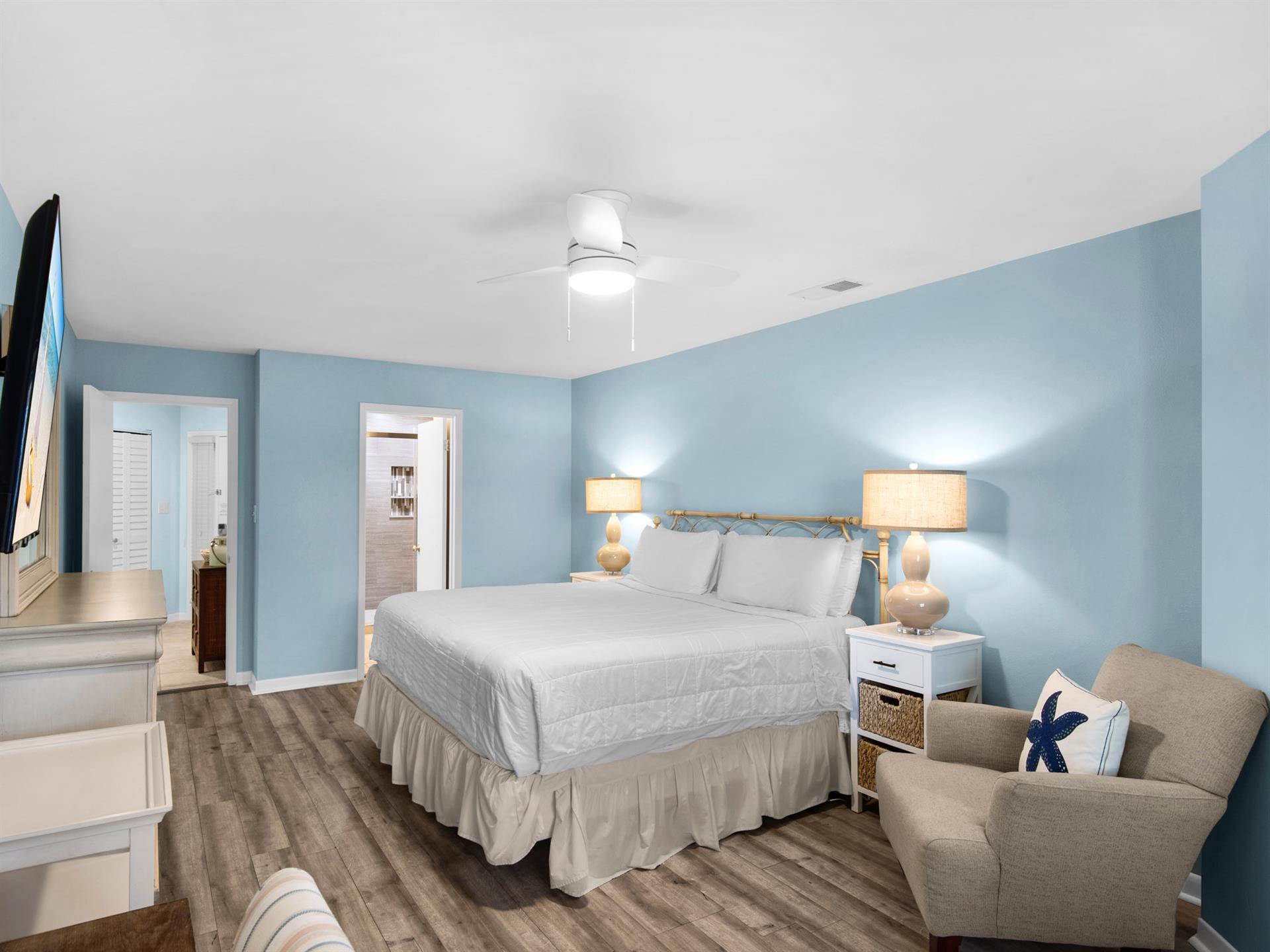 Unwind in your serene bedroom with calming blue walls, plush bedding, and warm lighting that creates the perfect peaceful retreat.