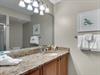 Freshen up in your elegant bathroom featuring granite countertops, soft lighting, and cheerful coastal artwork.