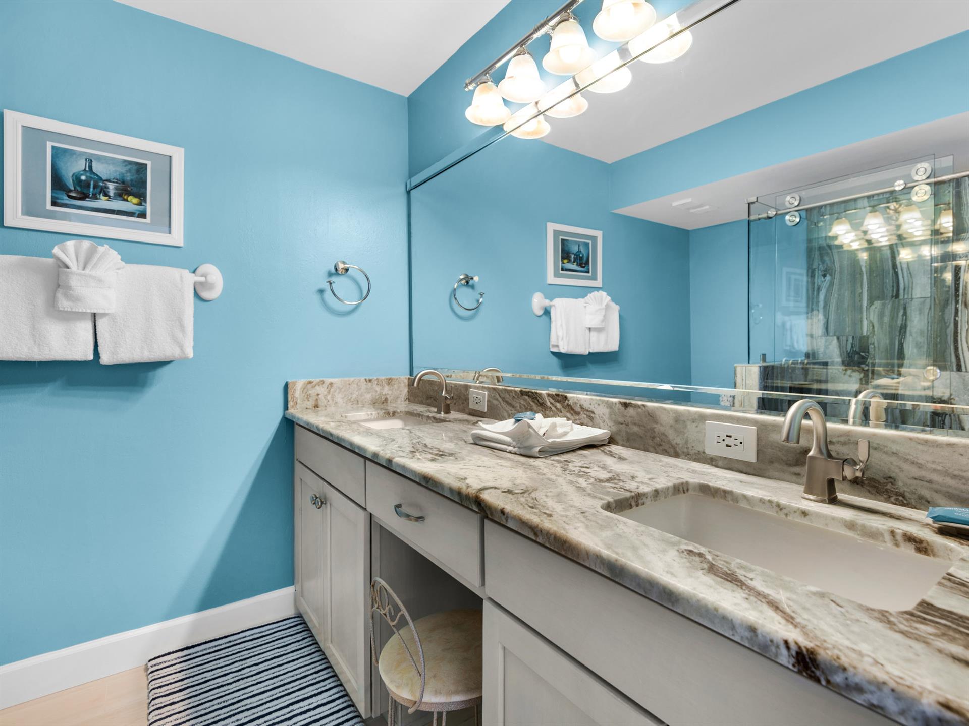 Refresh in your elegant bathroom with marble countertops, dual sinks, and cheerful blue walls that brighten every morning routine.