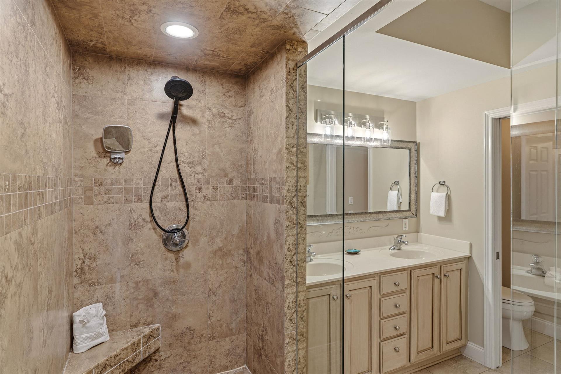 Bathroom 1 Unwind in your private spalike bathroom featuring a luxurious stone shower with bench and dual vanity space for getting ready.