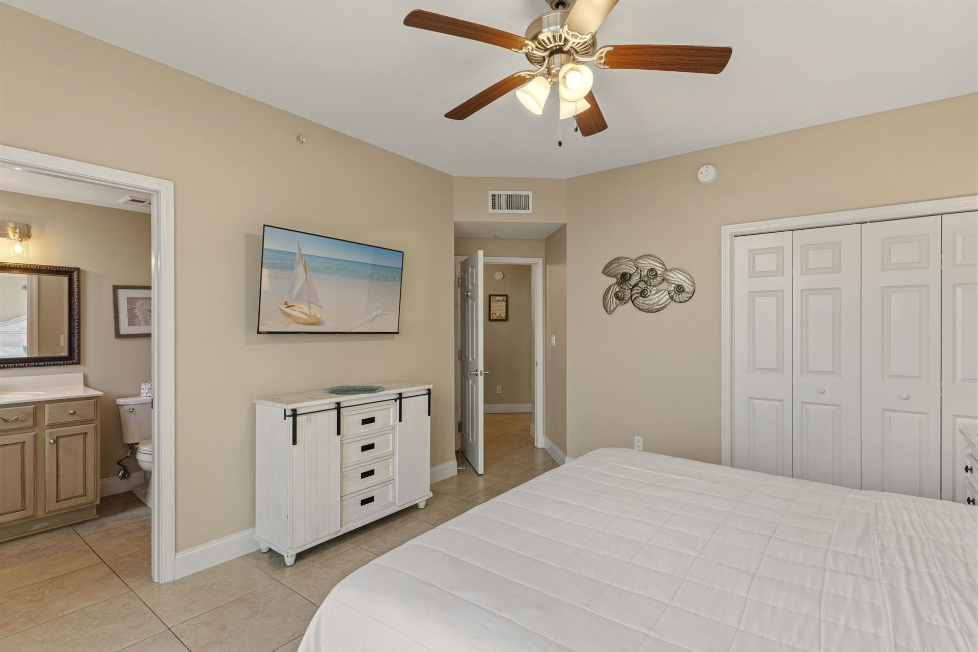 Bedroom 2 features a comfortable bed, coastalthemed artwork, and ceiling fan to keep you cool.